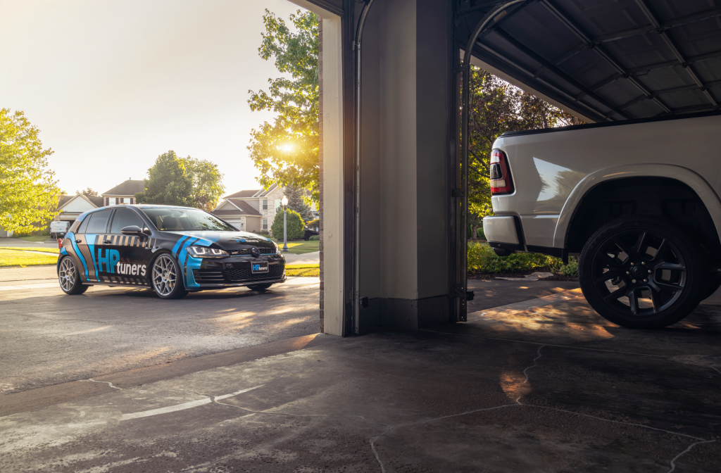 HP Tuners branded Golf GTI parked outside a garage with a Ford truck, 